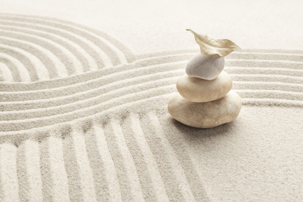 Fondo de arena con piedras de mármol zen apiladas en concepto de mindfulness.